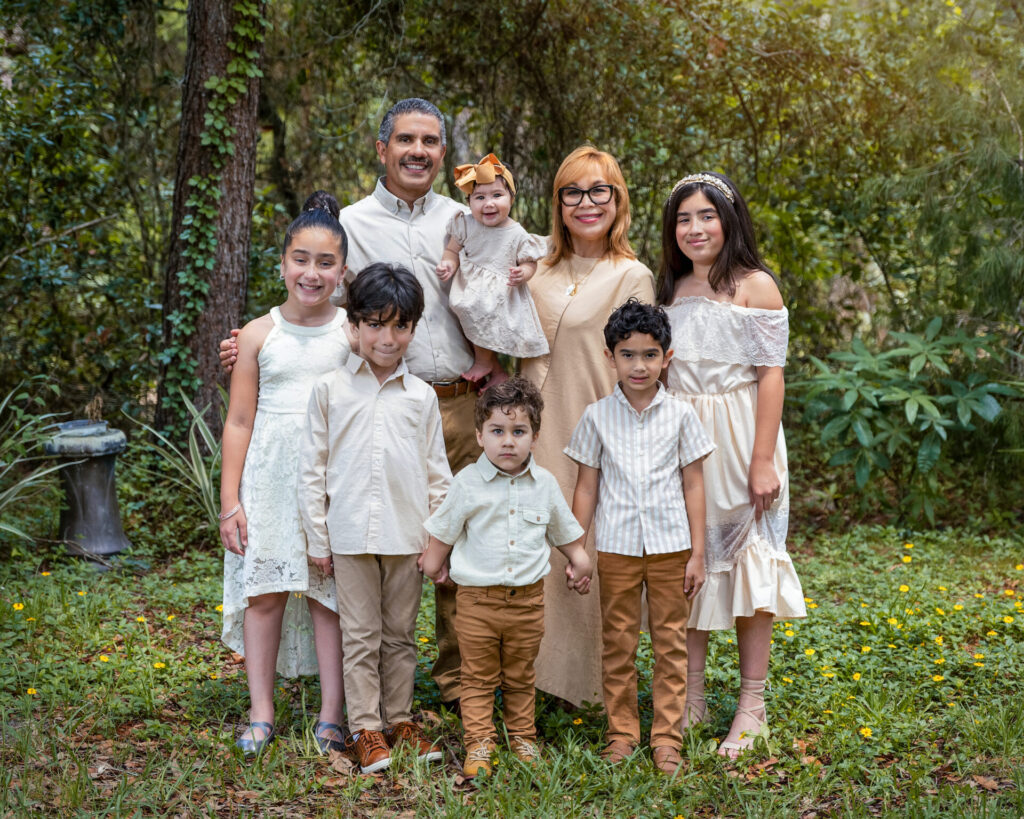 Family posinFamily posing for a portrait in a forested area, wearing coordinated neutral-colored outfits, captured by Spring Hill Florida's Family photographer JCenteno Photography.g for a photoshoot in a lush green outdoor setting, wearing coordinated beige and white outfits, capturing authentic and joyful moments. Family posing for a portrait in a forested area, wearing coordinated neutral-colored outfits, captured by Spring Hill Florida's Family photographer JCenteno Photography.