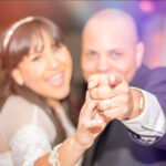 Smiling couple pointing at the camera, showcasing a joyful moment from a wedding, captured by JCenteno Photography in Spring Hill, FL. The image highlights the couple's happiness and the photographer's skill in capturing lively wedding scenes.
