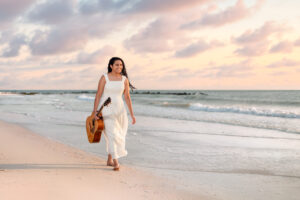 Senior portrait photography of a high school graduate walking along a beach in Tampa, Florida during golden hour.