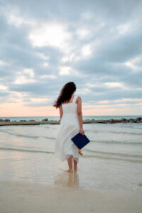 Senior portrait photography of a high school graduate walking along a beach in Tampa, Florida during golden hour.