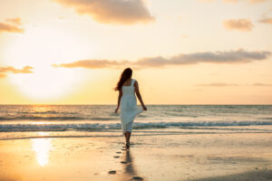 Senior portrait photography of a high school graduate walking along a beach in Tampa, Florida during golden hour.