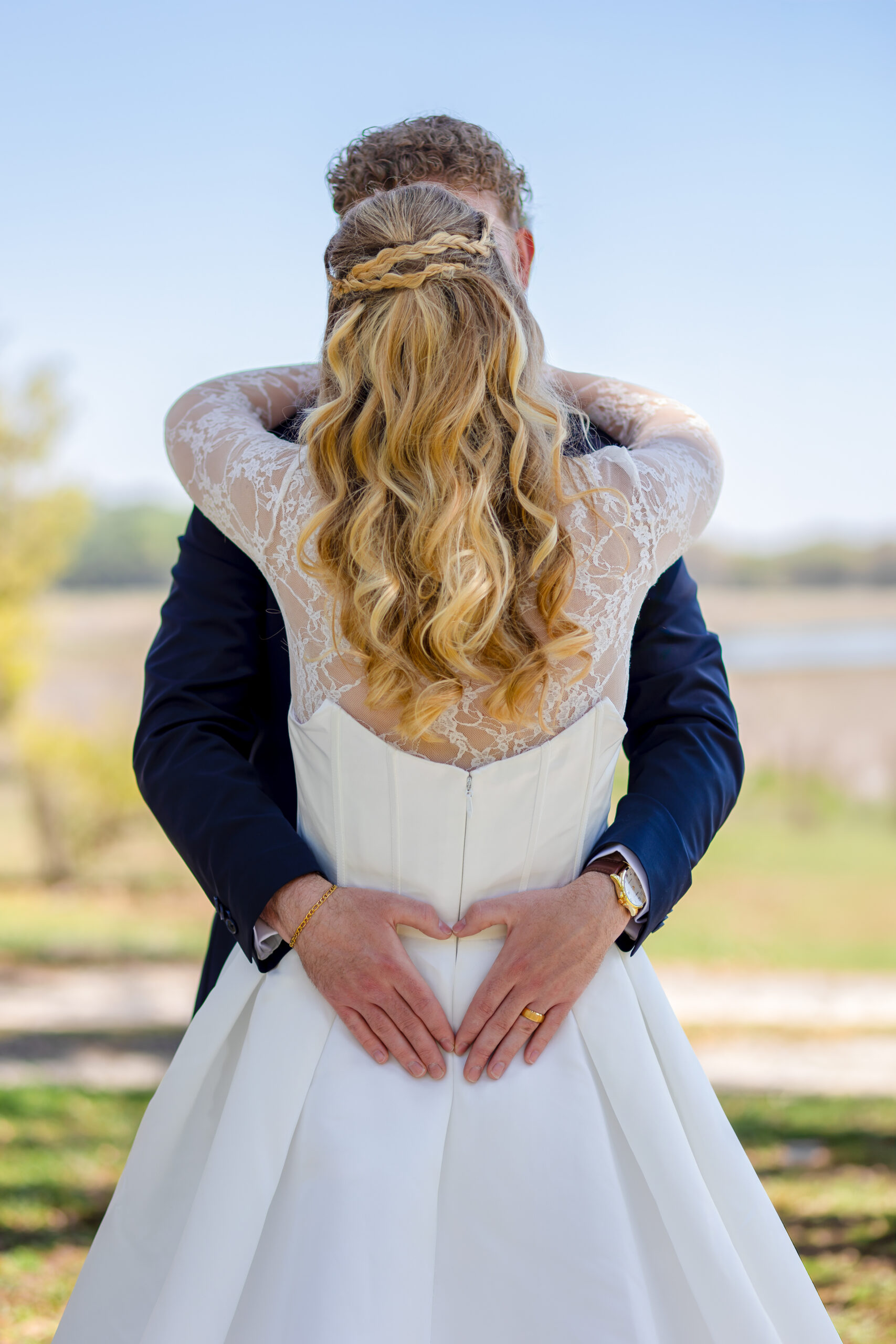 Candid wedding photography in Florida: A bride and groom embracing under the shade of a large oak tree during their outdoor wedding portrait session.